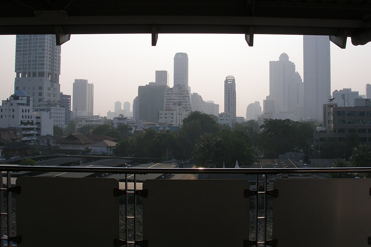 曼谷市中心资料景观,高层建筑、低矮社区和树木分布在朦胧天空下。