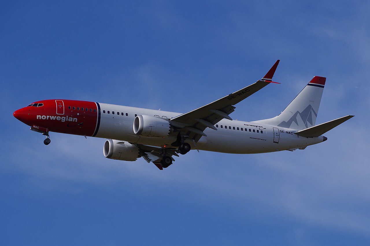 资料照片中的挪威航空波音737-8 MAX正在下降，起落架已经放下，背景为蓝天。