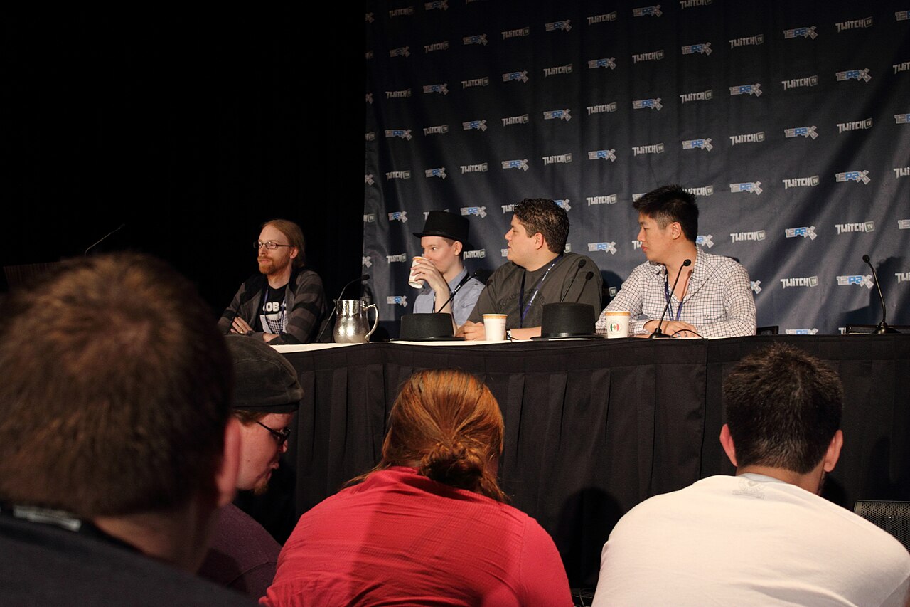 资料照片：四名 Mojang《我的世界》开发者坐在 PAX Prime 2012 论坛舞台上，前景可见观众。