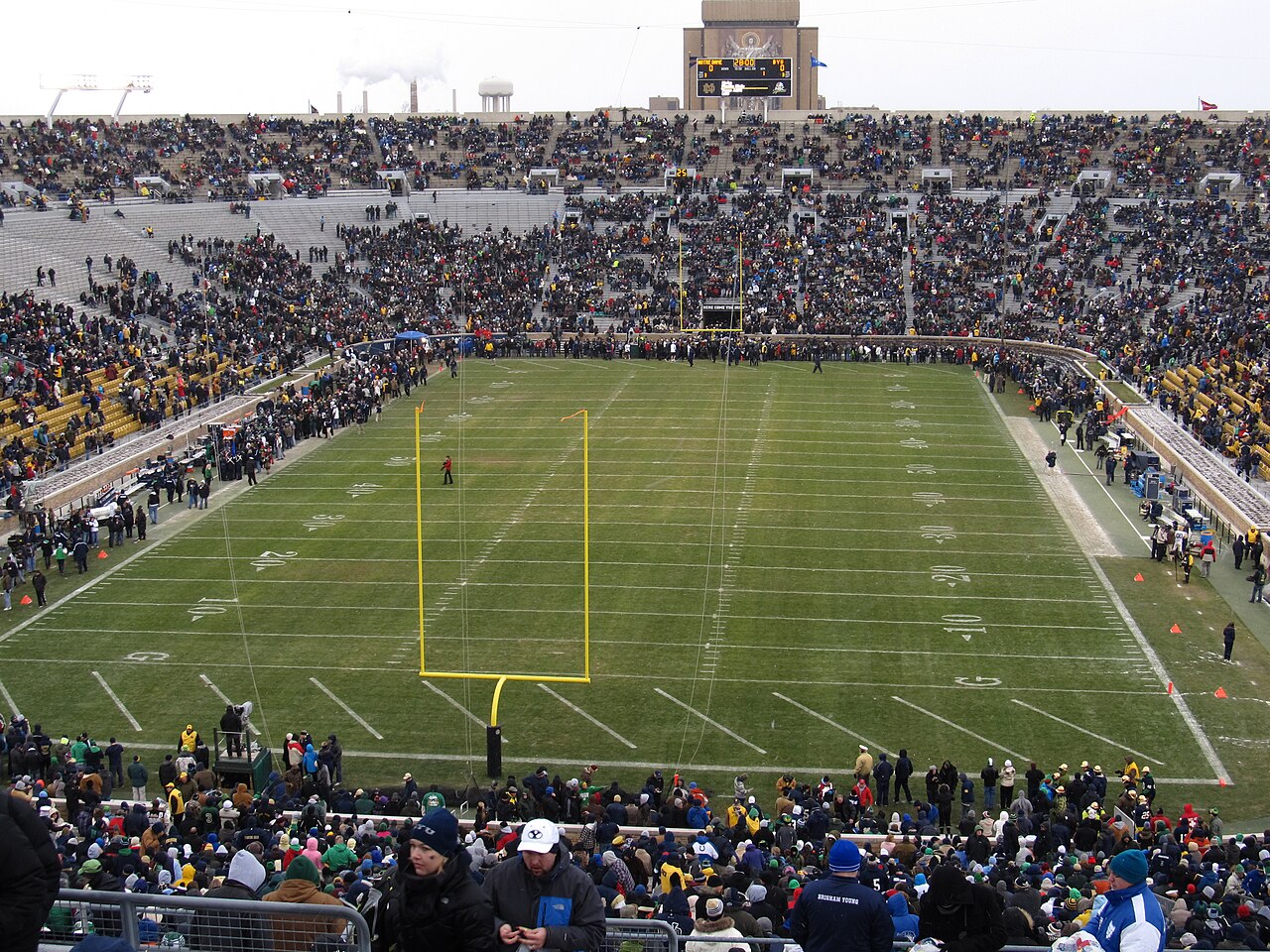 Notre Dame Stadium 的资料照片,可见带有码线的橄榄球场、黄色球门柱、看台观众和记分牌。