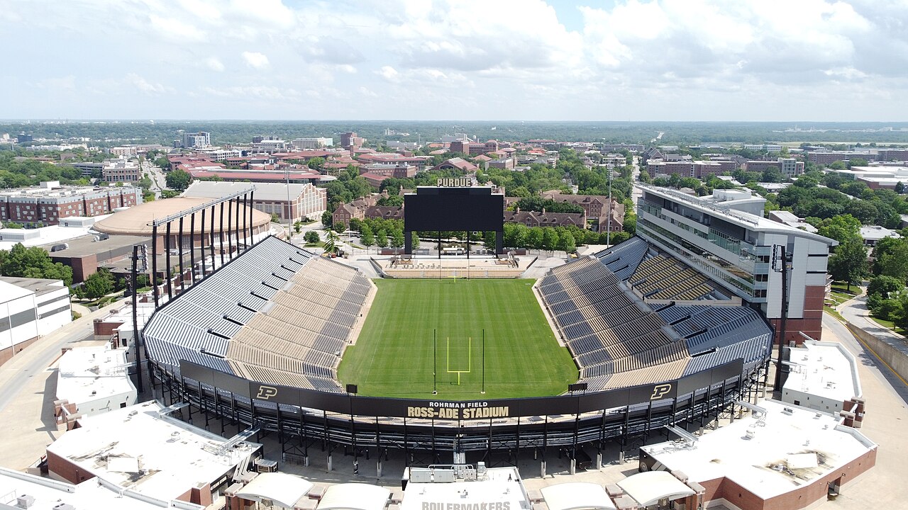 Ross-Ade Stadium 的资料航拍图,可见空置的橄榄球场、球门柱、环绕看台、Purdue 记分牌和校园建筑。