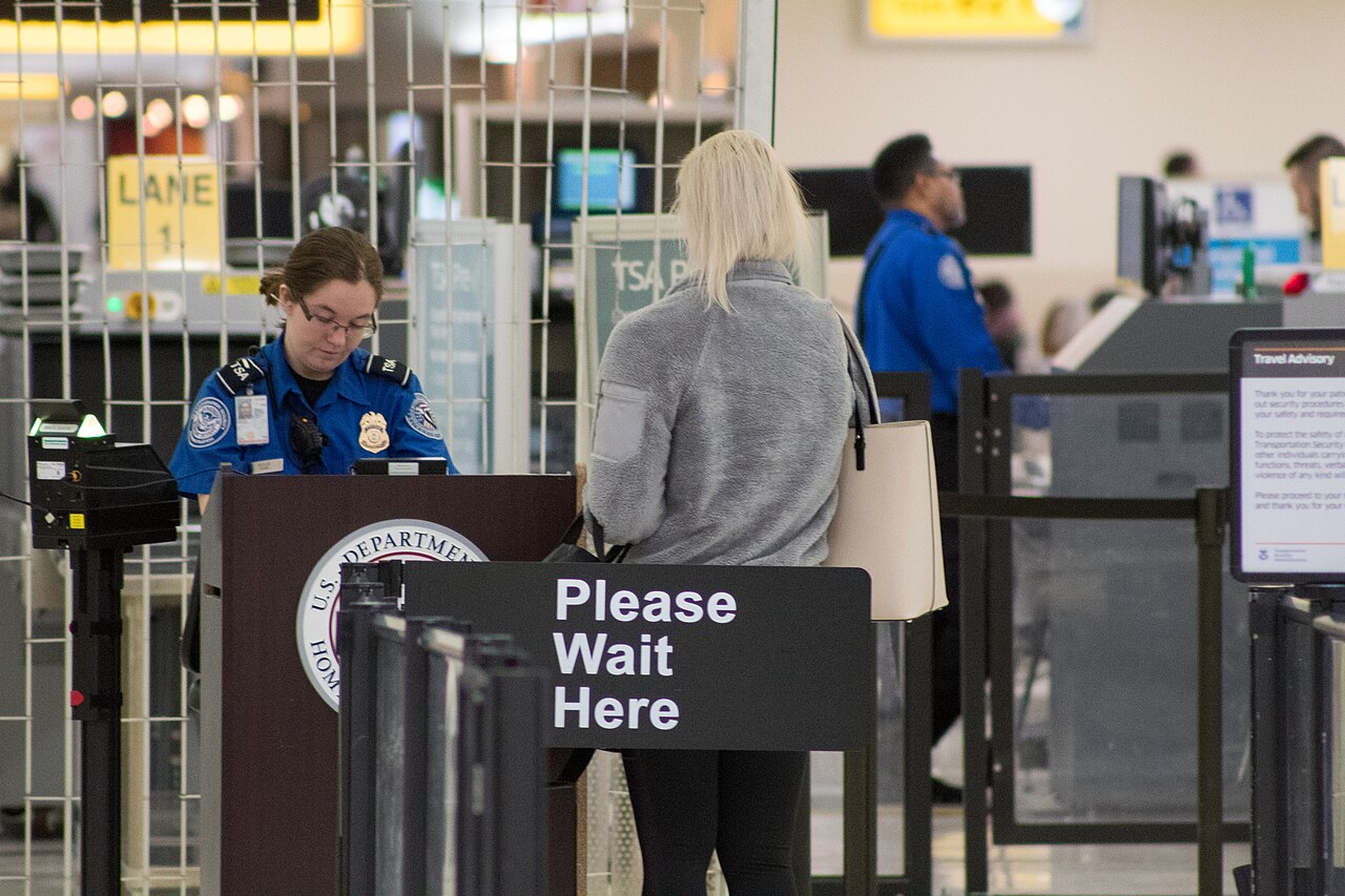 机场安检点内 TSA 工作人员正在核验旅客身份证件。